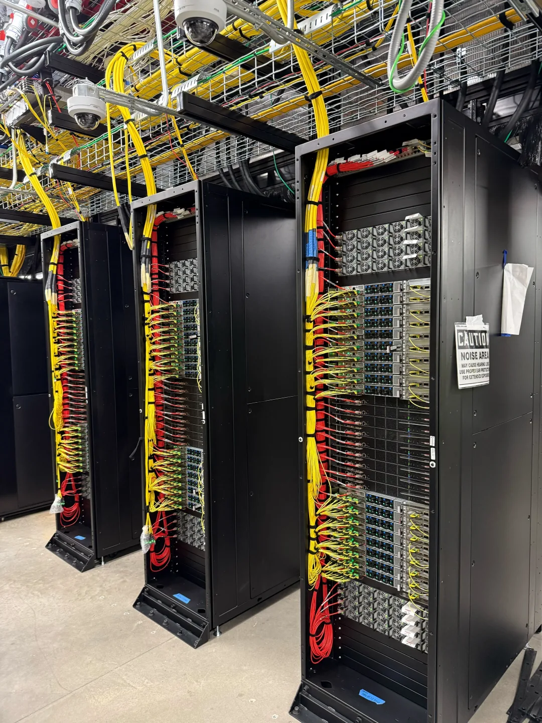 OpenAI 公告入面展示嘅 Stargate data center server rack,同一排排黃色同紅色網絡線