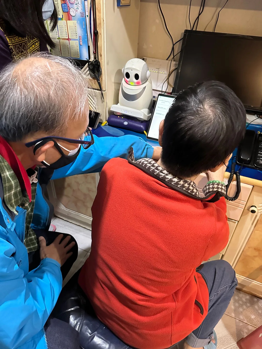 長者、照顧者同 Ka Ka 社交機械人一齊望住平板電腦,測試日常互動功能