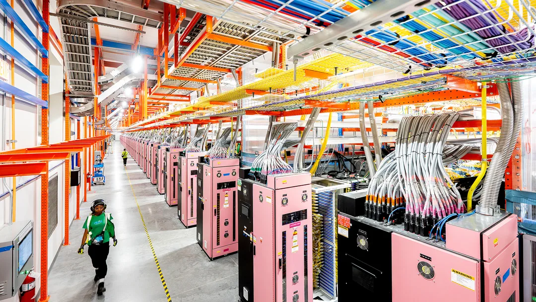 AWS Project Rainier data center 入面，技術員行過一排排 AI server 同電纜